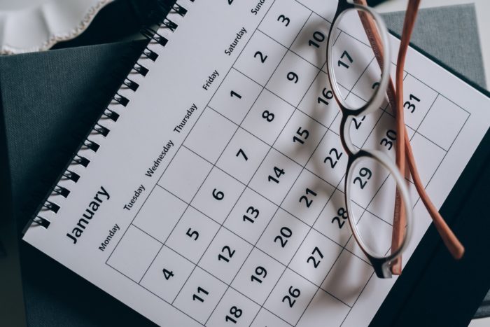 A pair of reading glasses sitting on top of a calendar with the month of January showing.
